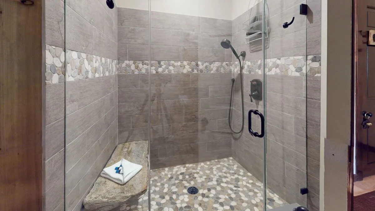 A serene shower area with a natural stone bench and decorative tile accents, capturing a sense of tranquility and rejuvenation. The thoughtful design encourages moments of relaxation and self-care, echoing the feel of a high-end spa.