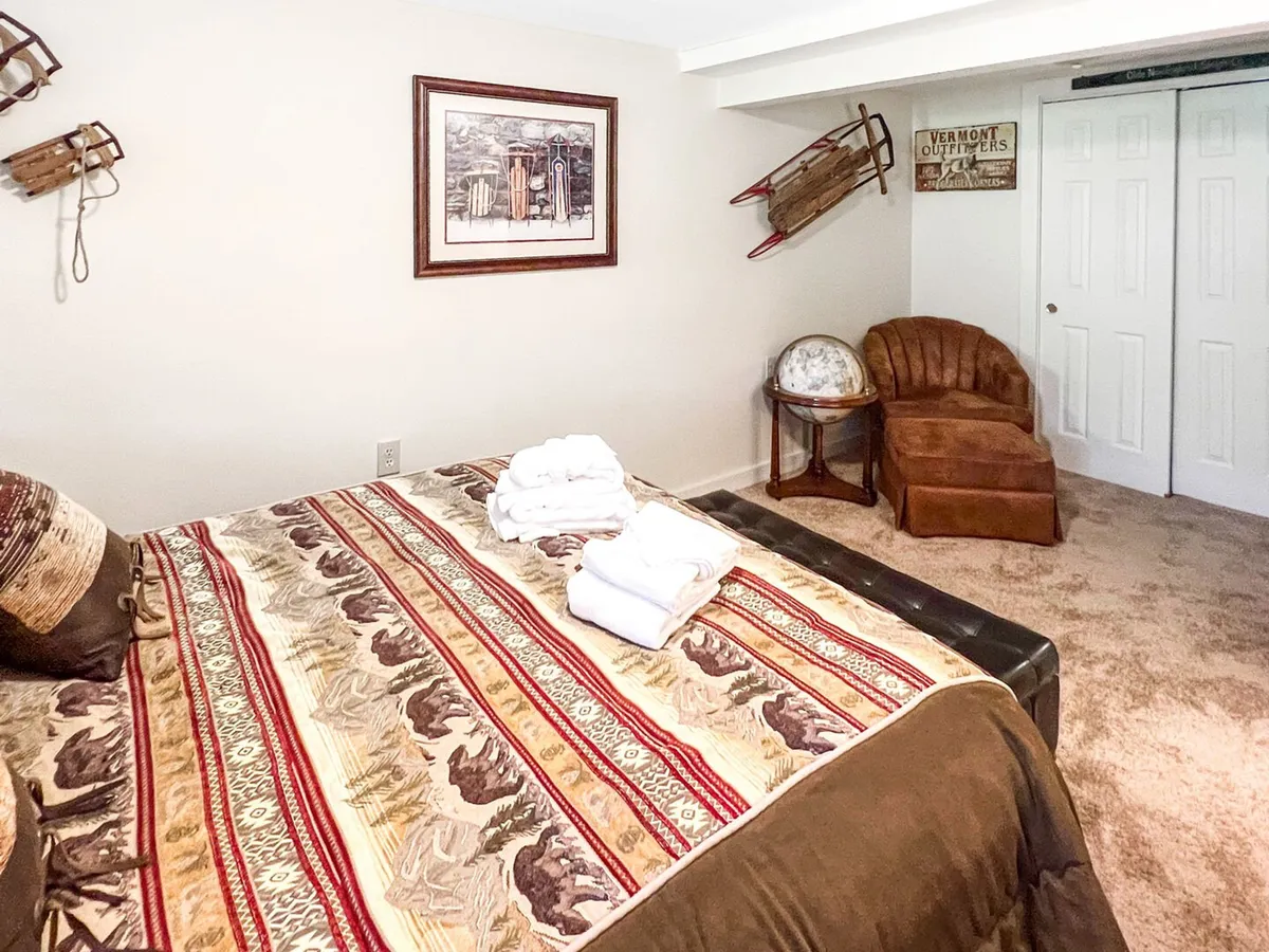 This room shows a bedroom with patterned bedding, framed artwork, sleds mounted on the wall for a playful touch, an accent chair, and a globe stand. The space feels bright and welcoming, offering a retreat for quiet time or restful sleep.
