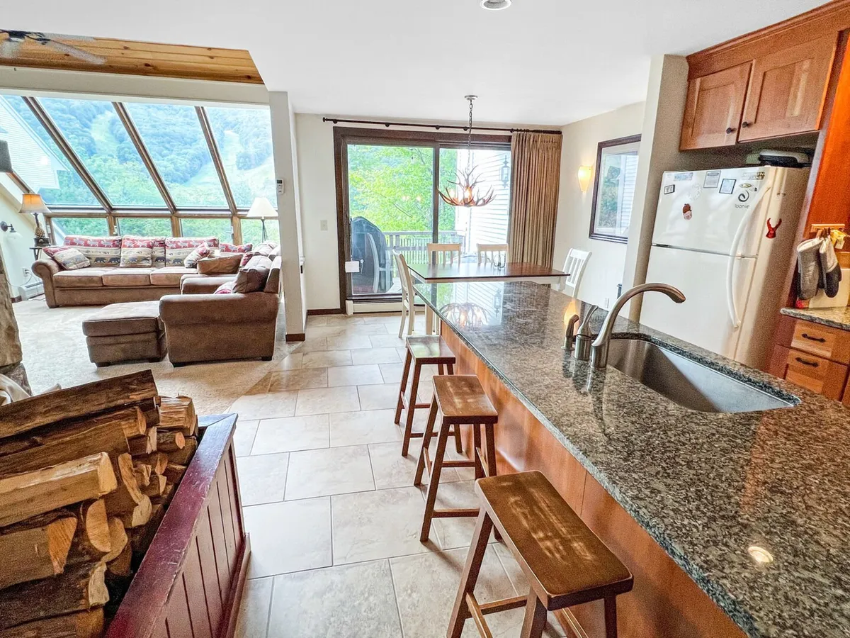 An inviting open-plan kitchen and seating area with large windows that frame a view of the mountains. The image suggests a seamless indoor-outdoor lifestyle, with spaces for gathering after outdoor fun.